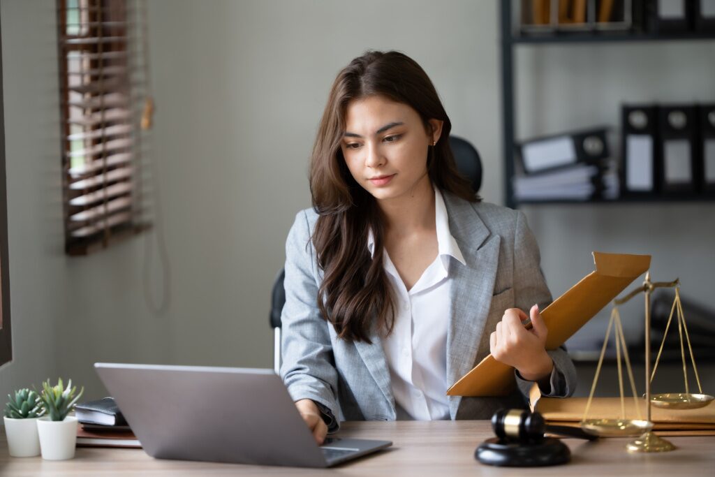 Lawyer Office. Statue Of Justice With Scales And Lawyer Working On A Laptop. Legal Law, Advice And Justice Concept.